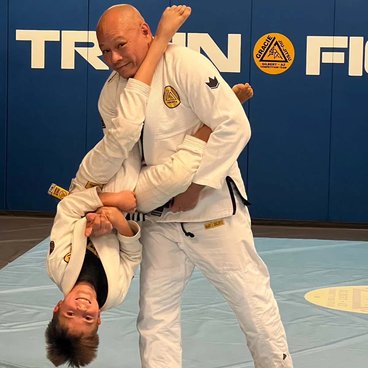Professor Quan Phu teaching a standing armbar to a smiling young student in Gracie Jiu-Jitsu class